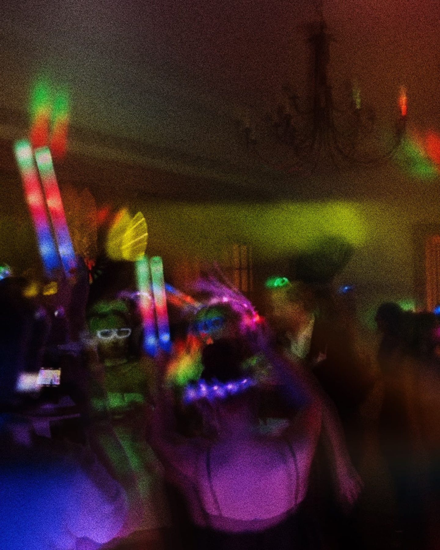 Party crowd with glow sticks under colourful lights